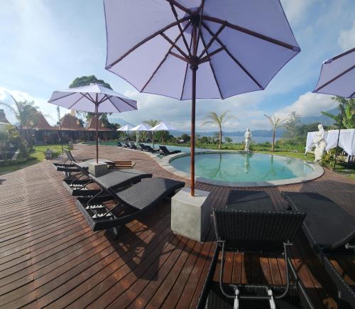a deck with chairs and a pool with an umbrella at Starlake Villa & Glamping in Kubupenlokan