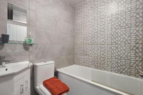 a bathroom with a toilet and a tub and a sink at Haw Hill House - modern 4 bed in Normanton
