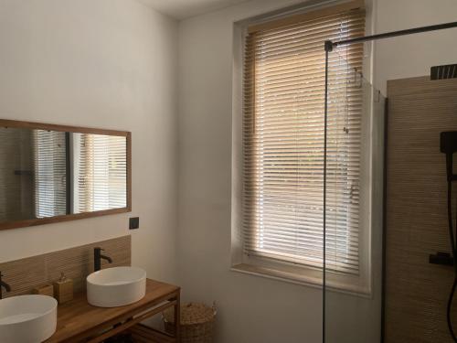 La salle de bains est pourvue de 2 lavabos et d'une fenêtre avec des stores. dans l'établissement Villa Les Roses, à Marseille