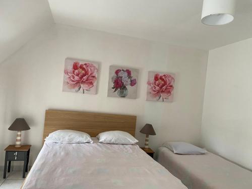 a bedroom with two beds and three paintings on the wall at Appartement 1 chambre et cuisine VIERVILLE-SUR-MER,plage du Débarquement in Vierville-sur-Mer