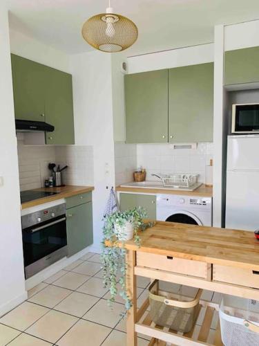 une cuisine avec des placards verts et une table en bois dans l'établissement Appartement T3 Tarnos cosy proche de la plage, à Tarnos