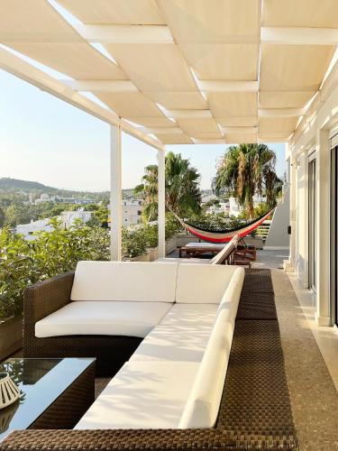 a white couch on a balcony with a hammock at Blue Bay Vouliagmeni Luxury Apartment in Athens