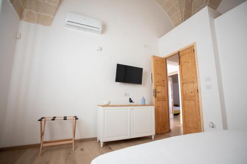 a white room with a bed and a tv on the wall at Ca’ Lezet in Guagnano