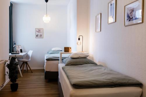 Duas camas num quarto com uma mesa e uma secretária. em Modernes Apartment Lieblingsfleck I 2 Schlafzimmer I 4 Betten I Zentrumsnah em Eberswalde