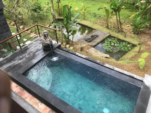 a swimming pool with a fountain in a garden at Sebatu Tulen Villa in Tegalalang