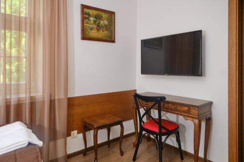 a room with a desk with a television and two chairs at Hotel Splendid in Pleven