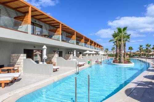 a resort swimming pool with lounge chairs and palm trees at Stella Palace Aqua Park Resort in Hersonissos