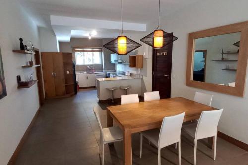 cocina y comedor con mesa de madera y sillas en Beachfront 2 Bedroom Apartment en Bain Boeuf