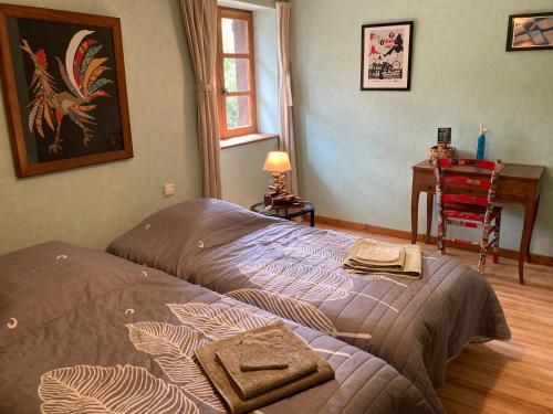 a bed in a bedroom with a table and a desk at B&B - Chambres d'Hôtes Acoucoula in Orthez