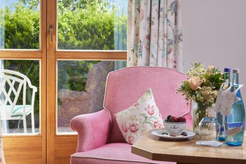 a pink chair in a room with a table at Relais & Châteaux Hotel Tennerhof in Kitzbühel
