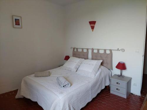 1 dormitorio con 1 cama con sábanas blancas y lámpara en Maison de César en Saint-Saturnin-dʼApt