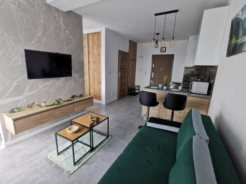 a living room with a green couch and a kitchen at Apartament Apres Ski in Karpacz