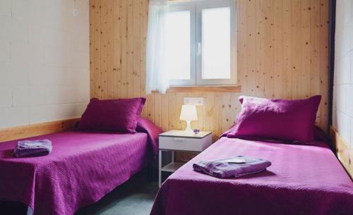 two beds in a room with purple sheets at Albergue A Nave de Ferreira in Lugo