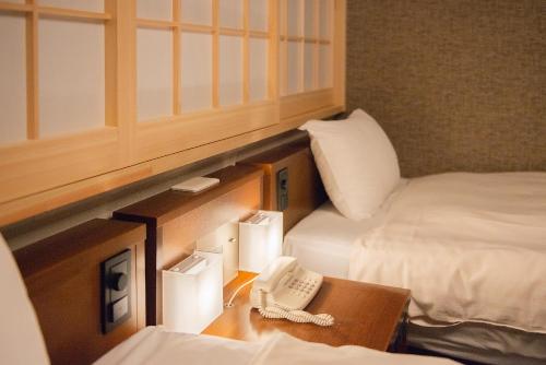 a room with two beds and a phone on a table at Shizuoka Town Hotel in Shizuoka