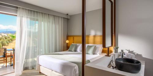 a bedroom with a bed and a bathroom with a sink at Stella Palace Aqua Park Resort in Hersonissos