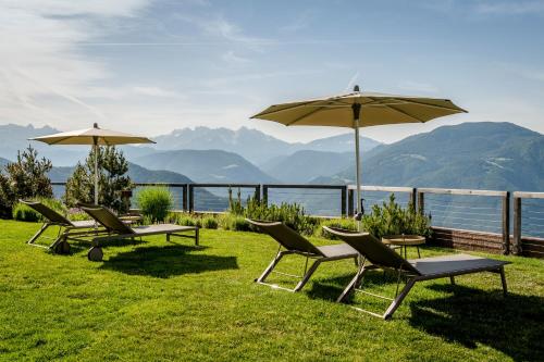 a group of chairs and umbrellas on the grass at Hotel Belvedere - Fine Dining, Hideaway & SPA in San Genesio Atesino