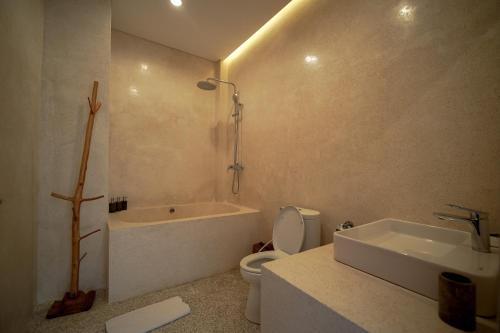 a bathroom with a tub and a toilet and a sink at Wakasuta House in Ubud