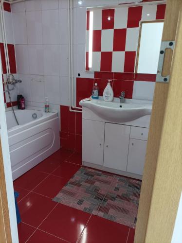 a red and white bathroom with a sink and a tub at Apartament două camere in Uricani