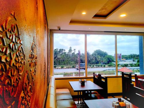 a restaurant with two tables and a large window at Sadanand's Highway Inn, Tumkur in Tumkūr