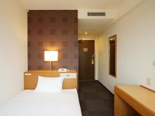 um quarto com uma cama e uma secretária com um candeeiro em Smile Hotel Towada em Towada