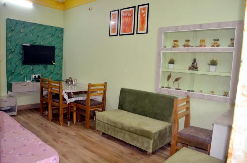 een woonkamer met een tafel en stoelen en een televisie bij Pinakin Homestay in Ujjain