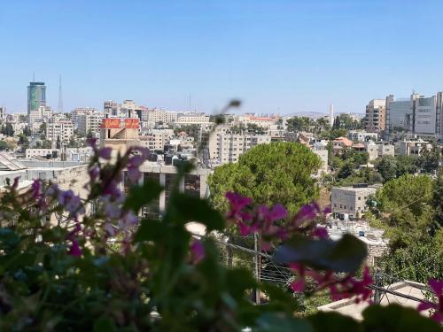 a view of a city with purple flowers in the foreground at Mizirawi Historic Hotel in Ramallah