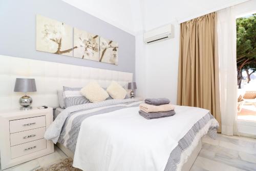 een witte slaapkamer met een bed en een raam bij Townhouse with pool view - Vime Reserva de Marbella in Marbella