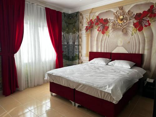 een slaapkamer met een groot bed met rode gordijnen bij NUS GRAND HOTEL 