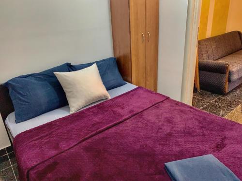 Una cama con una manta morada encima. en Sanja apartment en Prčanj