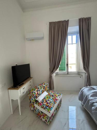 a bedroom with a bed and a chair and a television at Allegra Viareggio Appartamento & Affittacamere Guest house in Viareggio