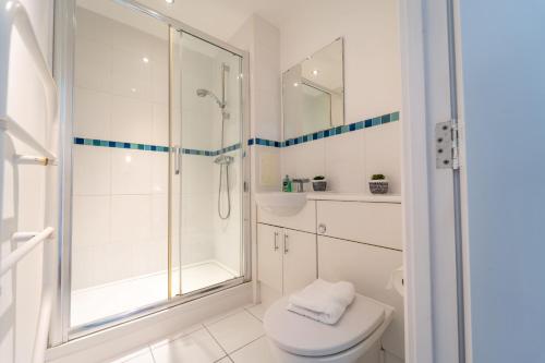 a white bathroom with a shower and a toilet at Spacious Apartment in Woking Town Centre in Woking