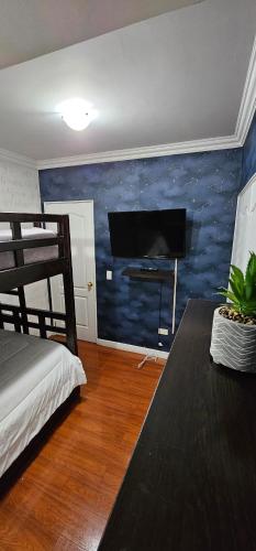 1 dormitorio con pared azul y TV de pantalla plana en Hermoso y lujoso apartamento de descanso, en Quito