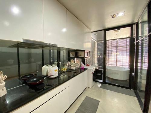 a kitchen with white cabinets and a black counter top at TownHome in Charoen Nakhorn 60 near BTS Iconsiam Asiatique and Chaophraya River Maximum 4 Guests in Bangkok