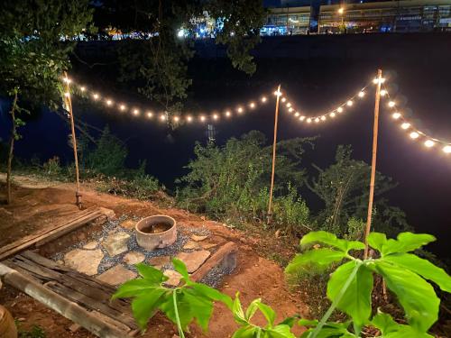 - un jardin avec des lumières et un foyer extérieur la nuit dans l'établissement HostelBed @ Phitsanulok, à Phitsanulok