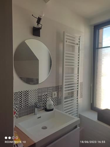 W białej łazience znajduje się umywalka i lustro. w obiekcie Ty Marok -proche des plage et des commerces w mieście Douarnenez