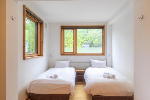 two beds in a room with two windows at Chalet Murasaki in Niseko