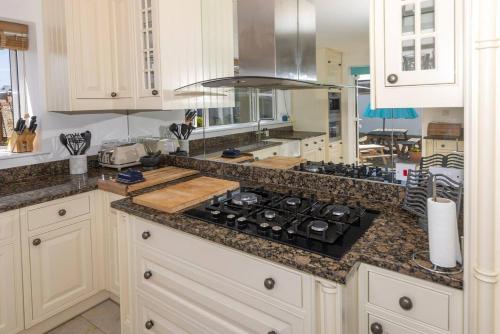 a kitchen with white cabinets and a stove top at Big Sky at Hive Beach in Burton Bradstock