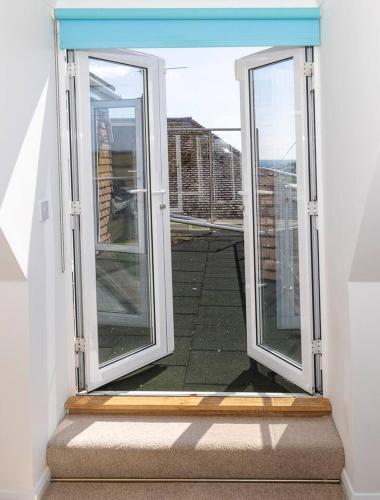 an open door to a balcony with a view at Big Sky at Hive Beach in Burton Bradstock