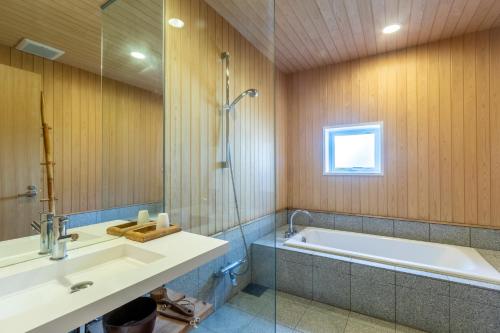 倶知安町にあるChalet Murasakiの浴槽、洗面台、シャワーを備えたバスルーム
