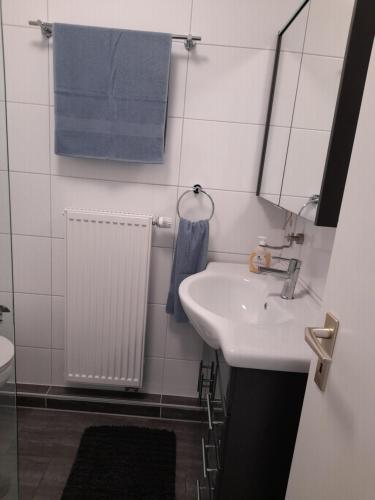 La salle de bains est pourvue d'un lavabo, d'un miroir et de serviettes bleues. dans l'établissement Ferienwohnung in Lemgo-Brake, 3 Zimmer, à Lemgo