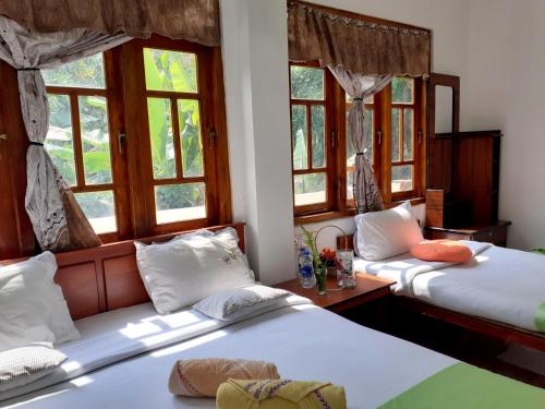 two beds in a room with windows at Subash Hotel in Nallathanniya