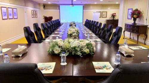 a meeting room with a long table with flowers on it at Habitat Hotel All Suites - Jeddah in Jeddah