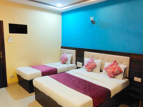 two beds in a room with a blue wall at Hotel Golden Galaxy - Santacruz East in Mumbai