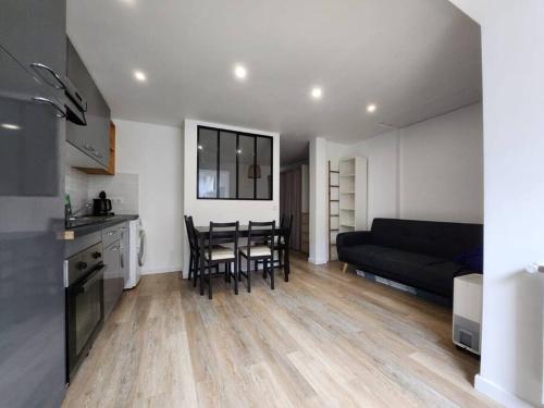 een keuken en een woonkamer met een tafel en een bank bij Charment studio proche Paris 15 in Malakoff