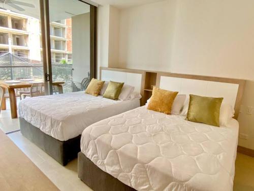 two beds in a bedroom with a balcony at Morros Zoe - Beautiful Apartment on Manzanillo Beach in Cartagena de Indias