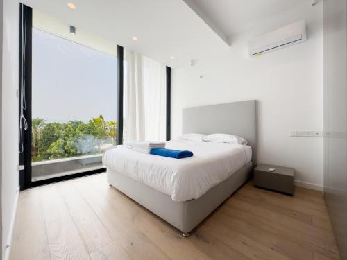a bedroom with a white bed and a large window at Sunset Park Villas in Paphos