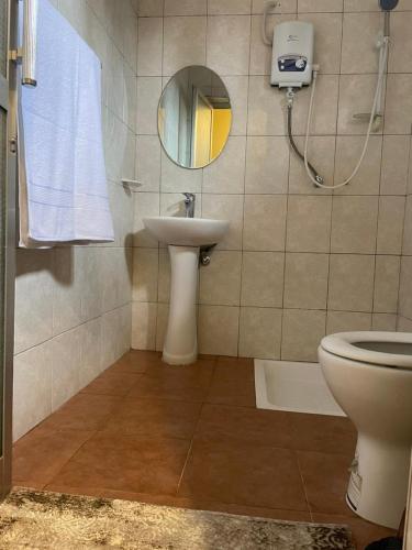 a bathroom with a sink and a mirror and a toilet at ULTRA HOME-Private House in Arusha