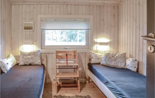 MosevråにあるAmazing Home In Oksbl With 3 Bedrooms, Sauna And Wifiのベッド2台、椅子、窓が備わる客室です。