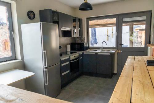 a kitchen with a stainless steel refrigerator and a wooden table at Au Repos de la Redoute in Aywaille