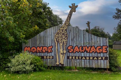 a giraffe is standing next to a sign at Au Repos de la Redoute in Aywaille